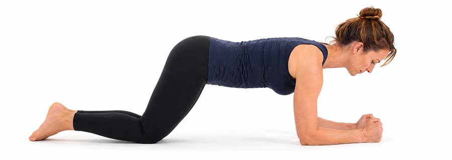 Vrouw is aan het planken, maar dan op haar knieën om deze rugoefening wat makkelijker te maken