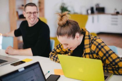 Tips voor een betere balans tussen werk en privé: 2 mensen achter laptop die plezier hebben.