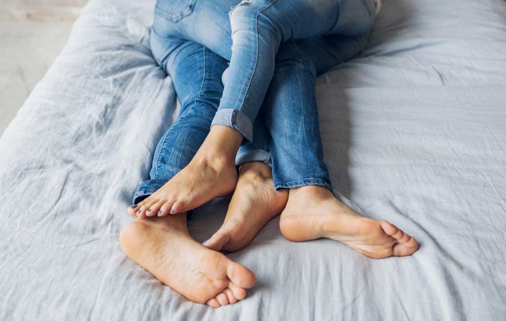 Stel verstrengeld in bed met kleding aan. Geen zin meer in seks met partner? Wat kun je doen om weer samen intiem te zijn?