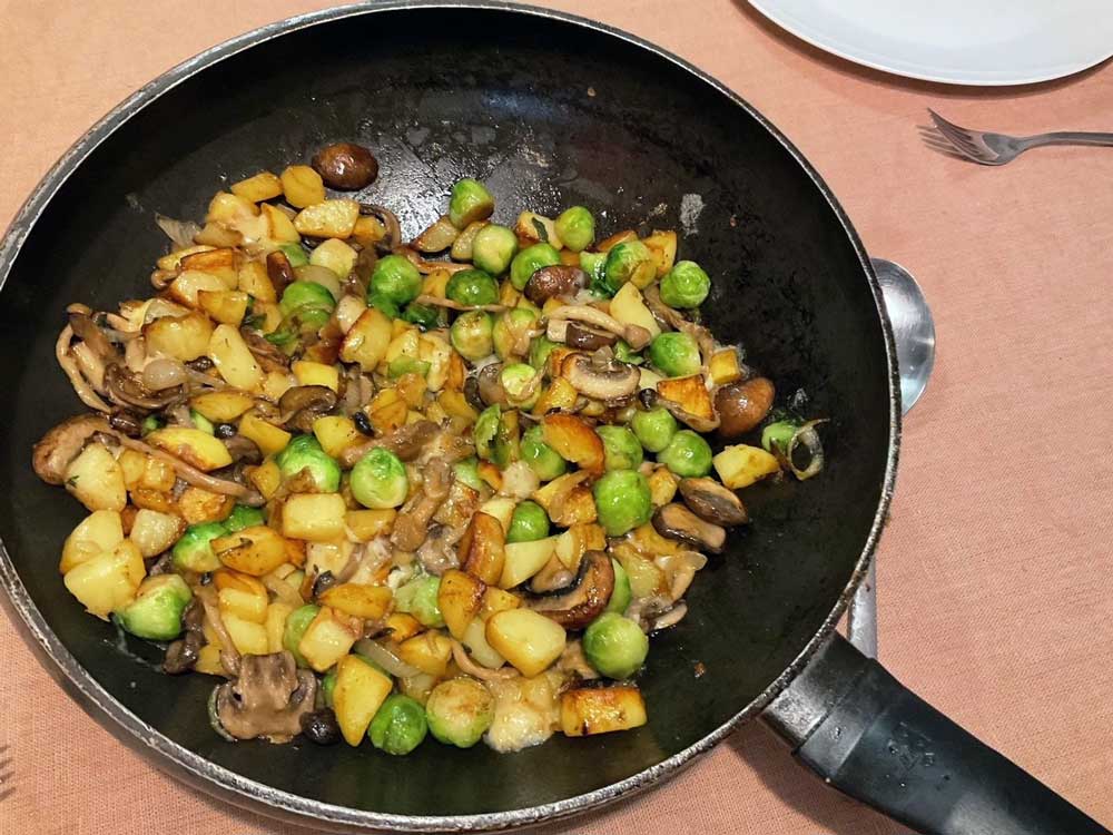 Gebakken spruitjes, met aardappeltjes, kaas en paddenstoelen. Bekijk het recept.