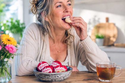 Vrouw eet aan de keukentafel een Babybel kaasje. Hoe gezond is dit?