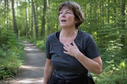 Vrouw in bos die zich benauwd voelt, terwijl ze weet dat er geen oorzaak is gevonden.