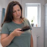 Haaruitval bij vrouwen: voeding, hormonen en wat helpt Vrouw met veel haar in haar haarborstel bij dit artikel over haaruitval bij vrouwen en de rol van voeding en hormonen