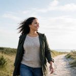Wat gebeurt er als je stopt met piekeren? Vrouw in de duinen die stopt met piekeren en haar piekergedachtes loslaat.