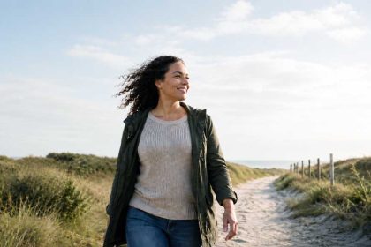 Vrouw in de duinen die stopt met piekeren en haar piekergedachtes loslaat.