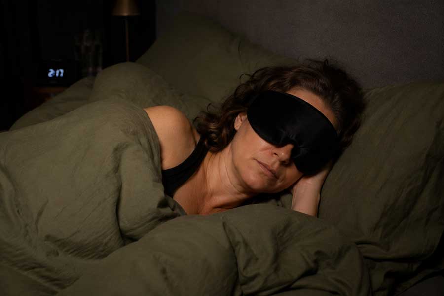Vrouw slaapt met slaapmasker op, om zo beter te slapen.